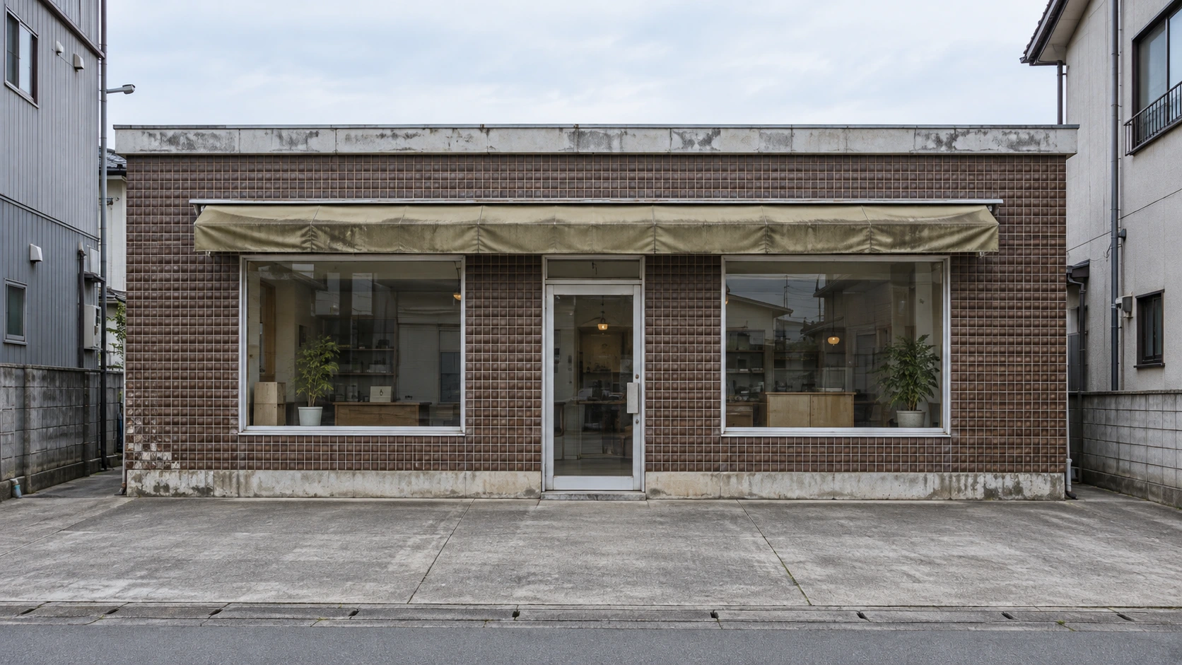改修前イメージ:古い茶色の外壁と庇のある平屋店舗